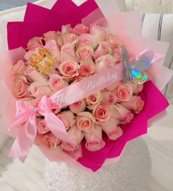 Bouquet of pale pink roses wrapped in pink paper with a birthday ribbon