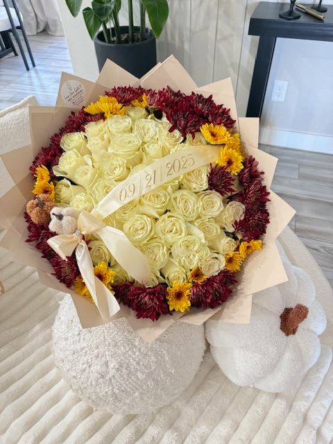 Golden Memory - An elegant arrangement of cream-colored roses surrounded by a crown of deep burgundy and sunflower-yellow blooms, delicately wrapped in soft blush-toned paper. Featuring a custom date ribbon and two charming decorative pumpkins, this bouquet is perfect for anniversaries, birthdays, or any unforgettable moment. A radiant celebration of love, warmth, and cherished memories.   Perfect for: Autumn gifts, anniversaries, meaningful dates, or seasonal surprises.