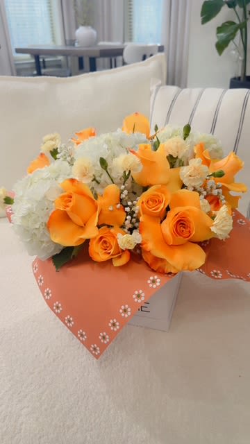 Orange roses and white flowers in a wrapped bouquet