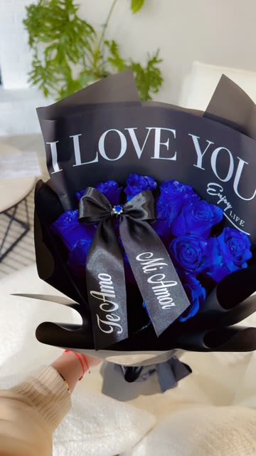 Bouquet of blue roses wrapped in black paper with a ribbon