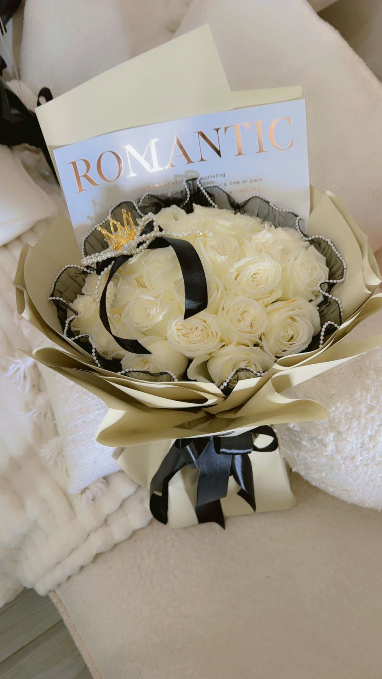 Bouquet of white roses wrapped in cream paper with black ribbon