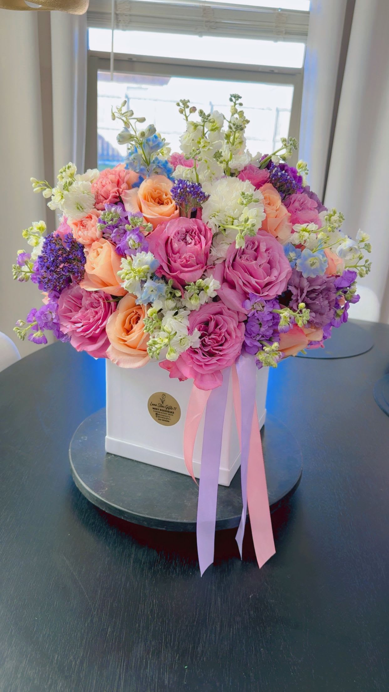 Pastel Garden Luxury Box - Soft, romantic, and beautifully designed — our Pastel Garden Luxury Box is a true floral statement   This elegant arrangement features a stunning mix of premium roses in blush and peach tones, complemented with delicate seasonal blooms in soft lavender, ivory, and light blue accents. Designed in a modern white box and finished with flowing ribbons, this piece feels fresh, artistic, and full of charm.  Perfect for birthdays, celebrations, or simply to brighten someone’s day with something truly special.   Designer-style arrangement by Lone Star Gifts  Premium flowers with soft pastel palette  Elegant box presentation with ribbon detail  Available for delivery in Midland, Odessa &amp; Gardendale  Same-day delivery available (order early) 