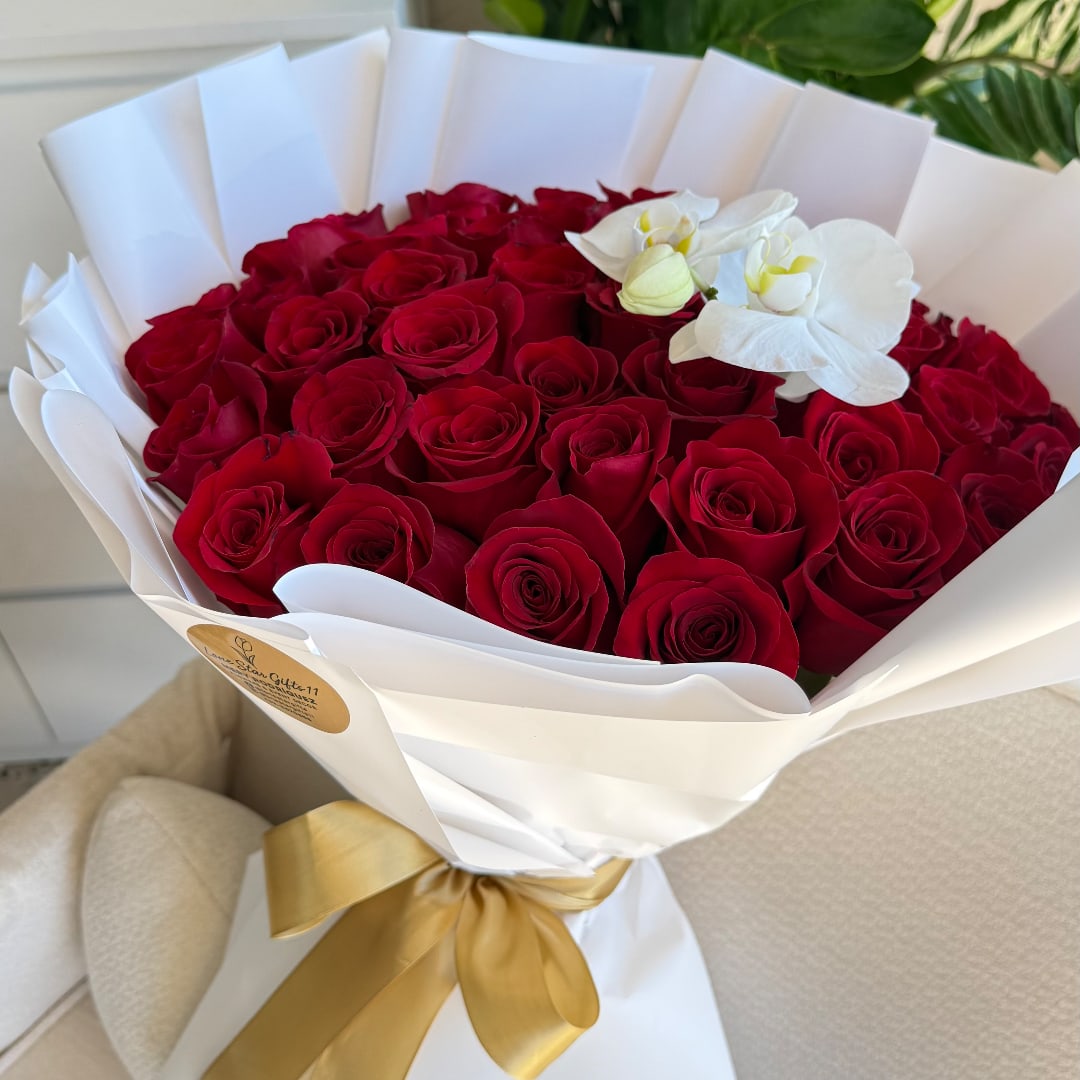 Bouquet of red roses with white orchids wrapped in white paper