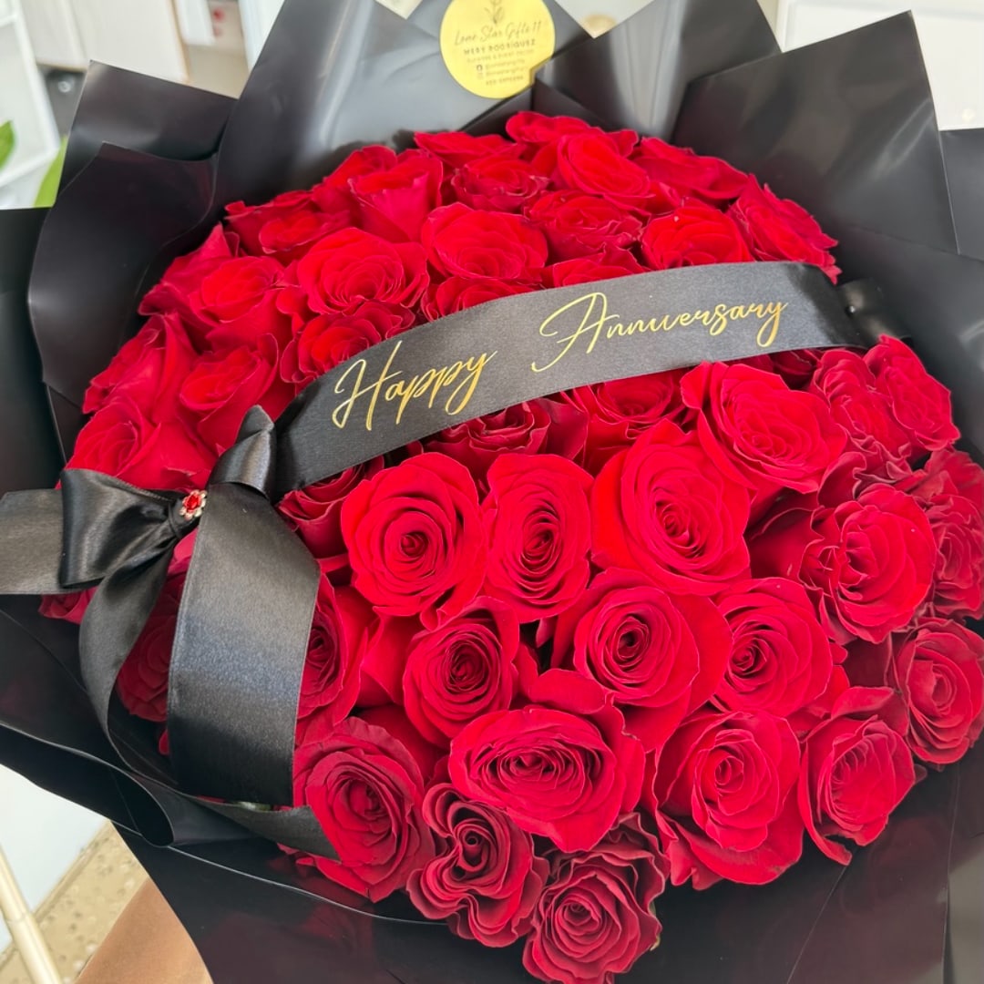 Bouquet of red roses wrapped in black paper with a Happy Anniversary ribbon