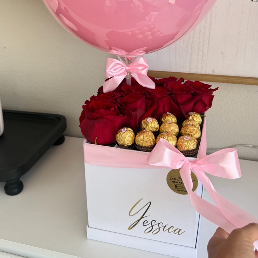 Red roses and gold chocolates in a pink gift box with a pink balloon
