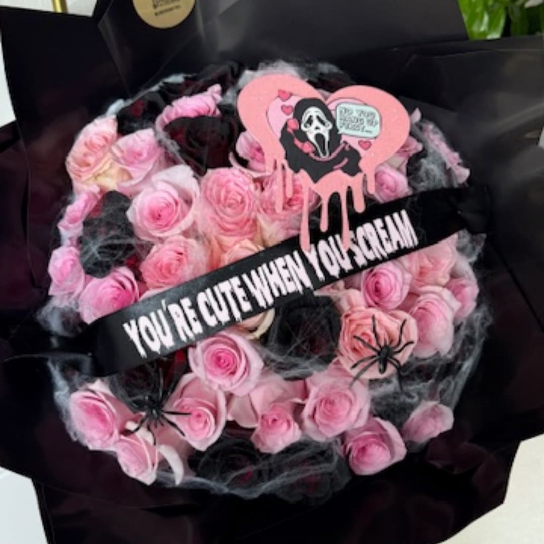 Pink rose bouquet with black wrapping and Halloween-themed decorations