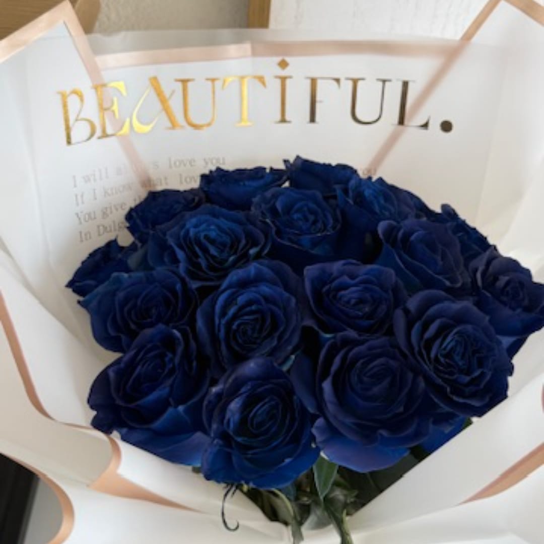 Bouquet of deep blue roses wrapped in white paper with gold lettering