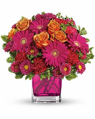 Bouquet of orange roses and magenta daisies in a pink glass vase