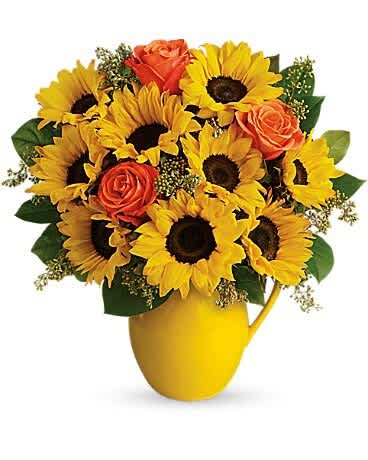 Sunflowers and orange roses arranged in a yellow pitcher vase