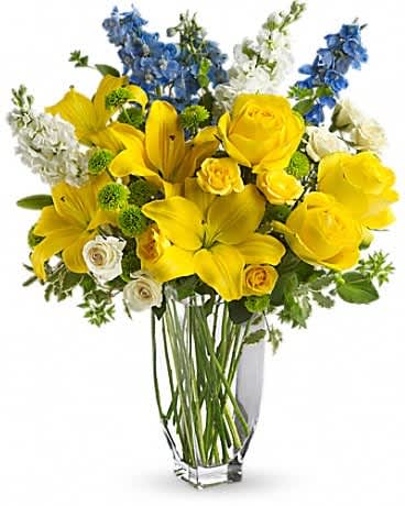 Yellow roses and lilies with blue and white flowers in a clear vase