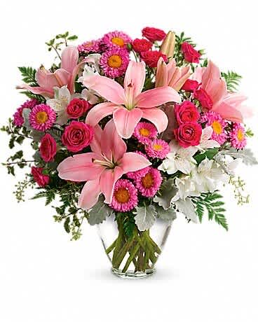 Pink lilies and mixed pink flowers in a clear glass vase