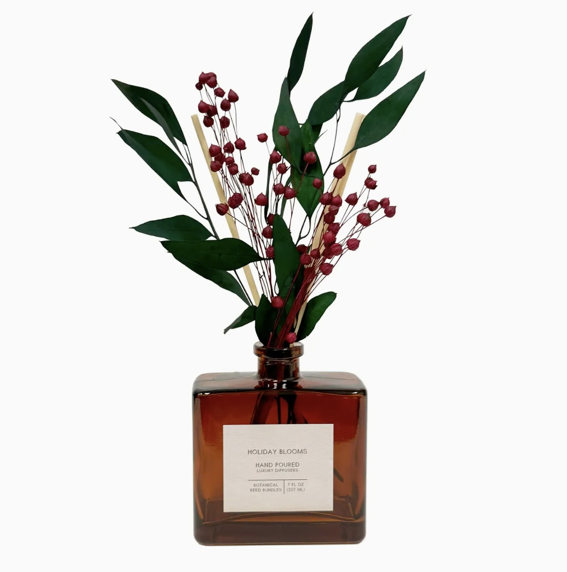 Amber reed diffuser bottle with red berry stems and green leaves