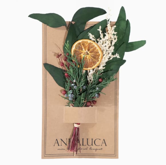 Dried bouquet with an orange slice and greenery on a kraft card