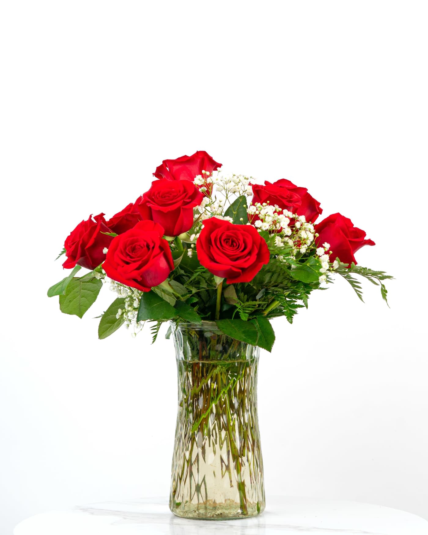 Red roses arranged in a clear glass vase with baby's breath