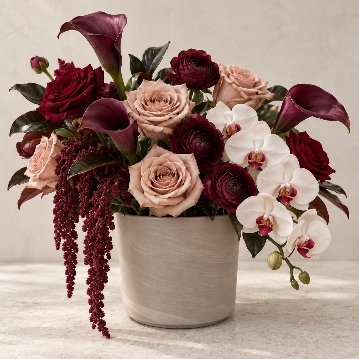 Bouquet of burgundy and blush roses with white orchids in a beige vase