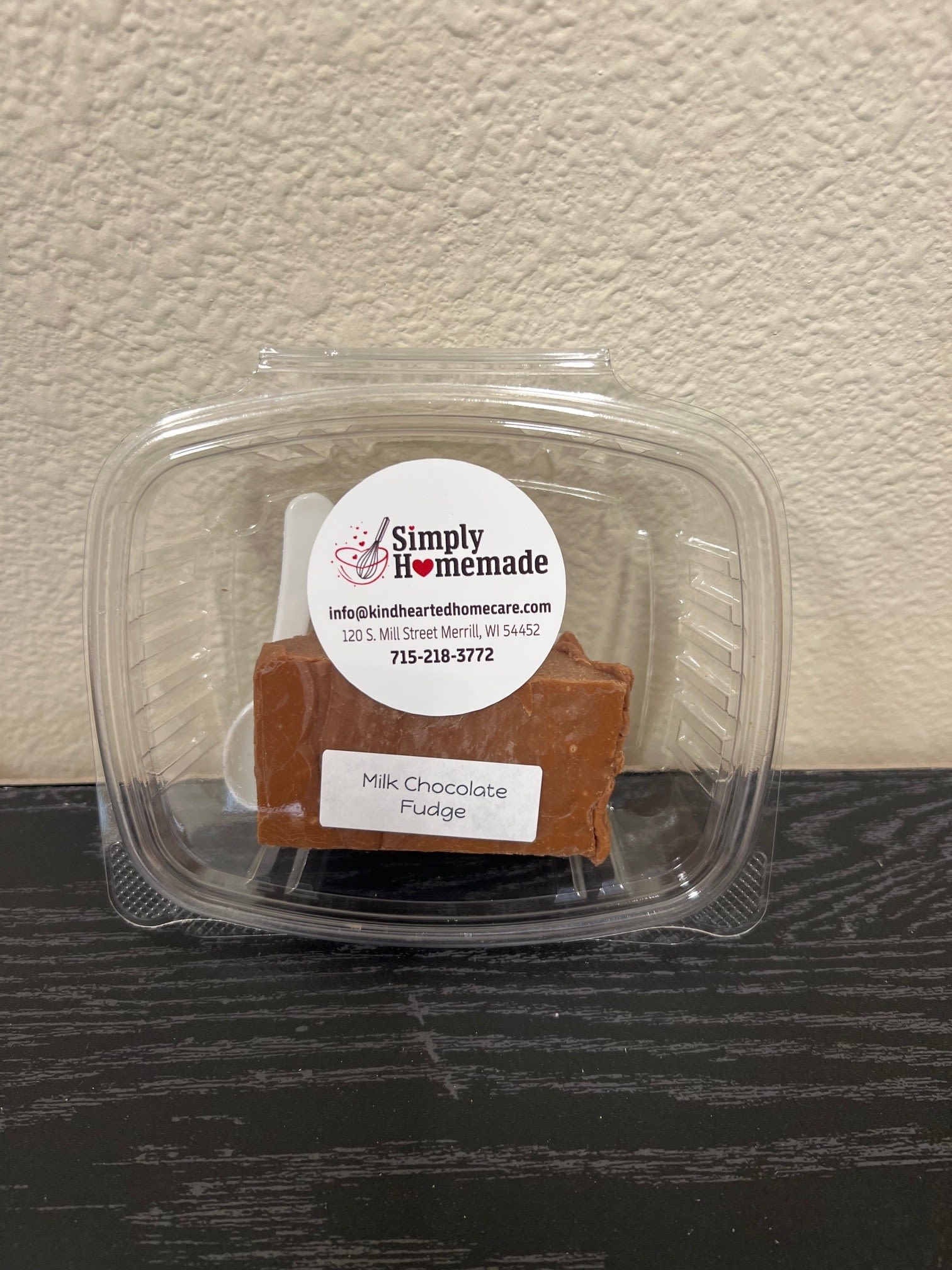 Plastic clamshell container holding a block of milk chocolate fudge