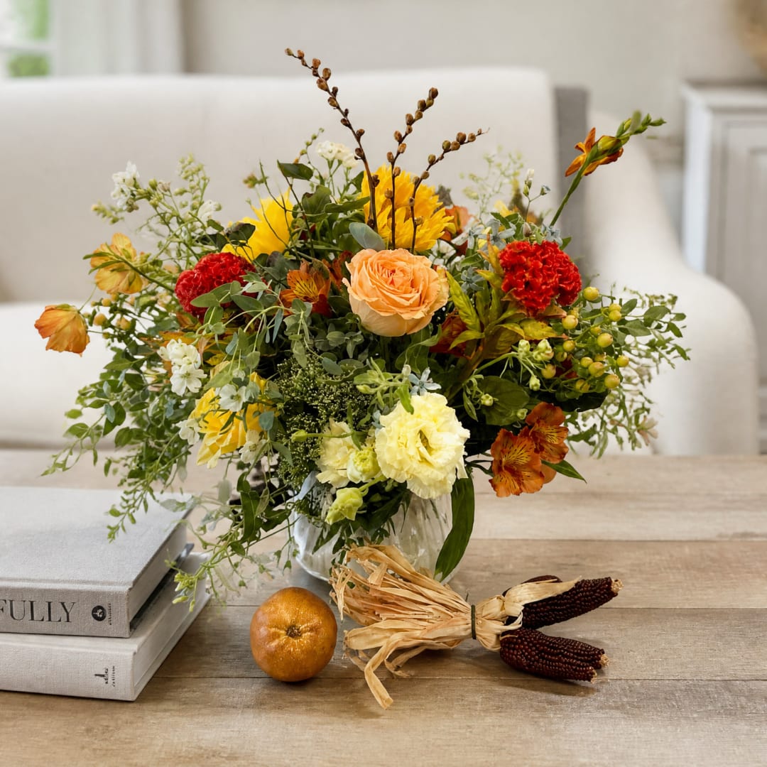 Mixed bouquet in a glass vase with yellow, peach, red, and white flowers