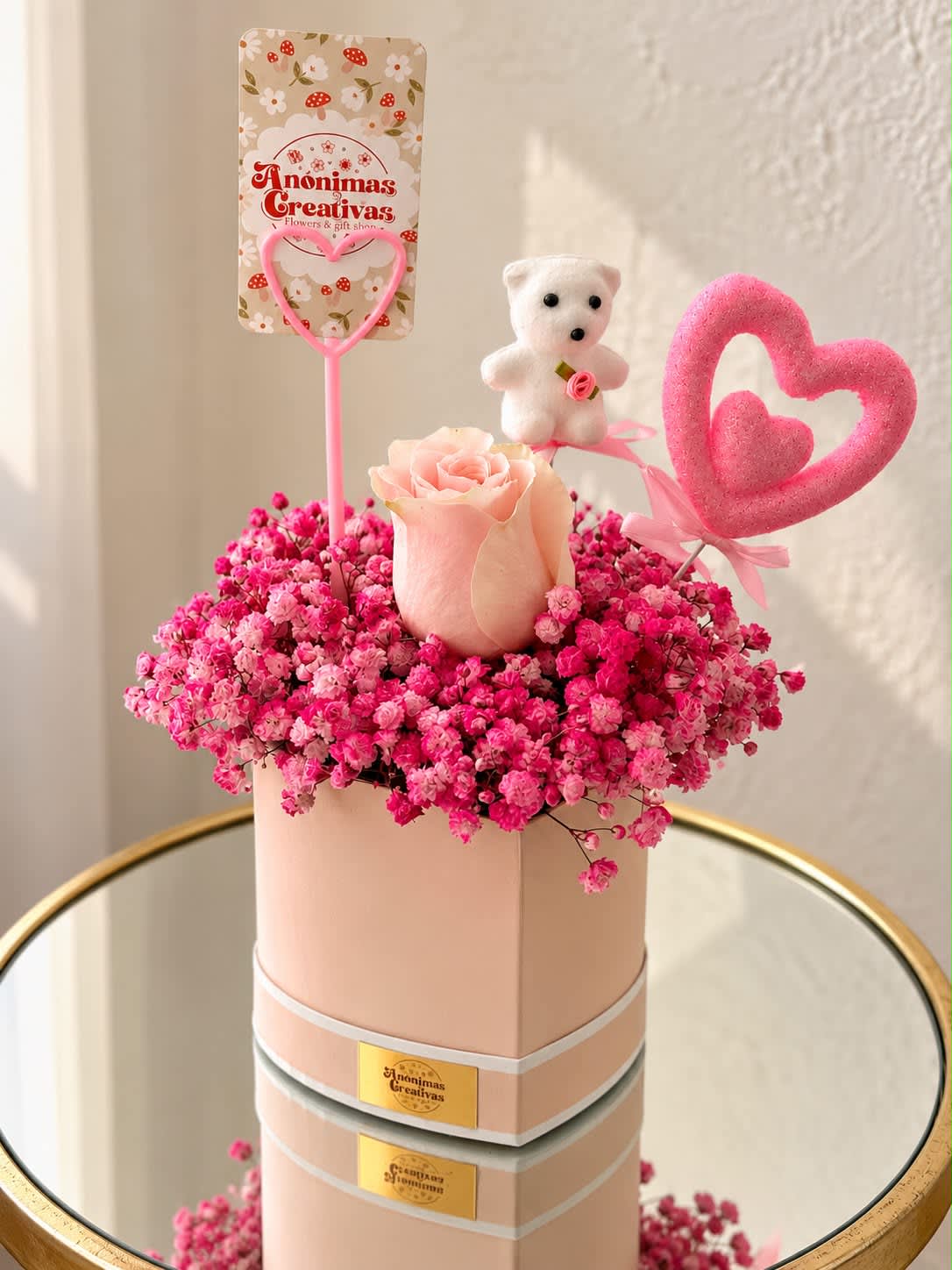 Pink rose arrangement in a round box with a teddy bear and heart toppers