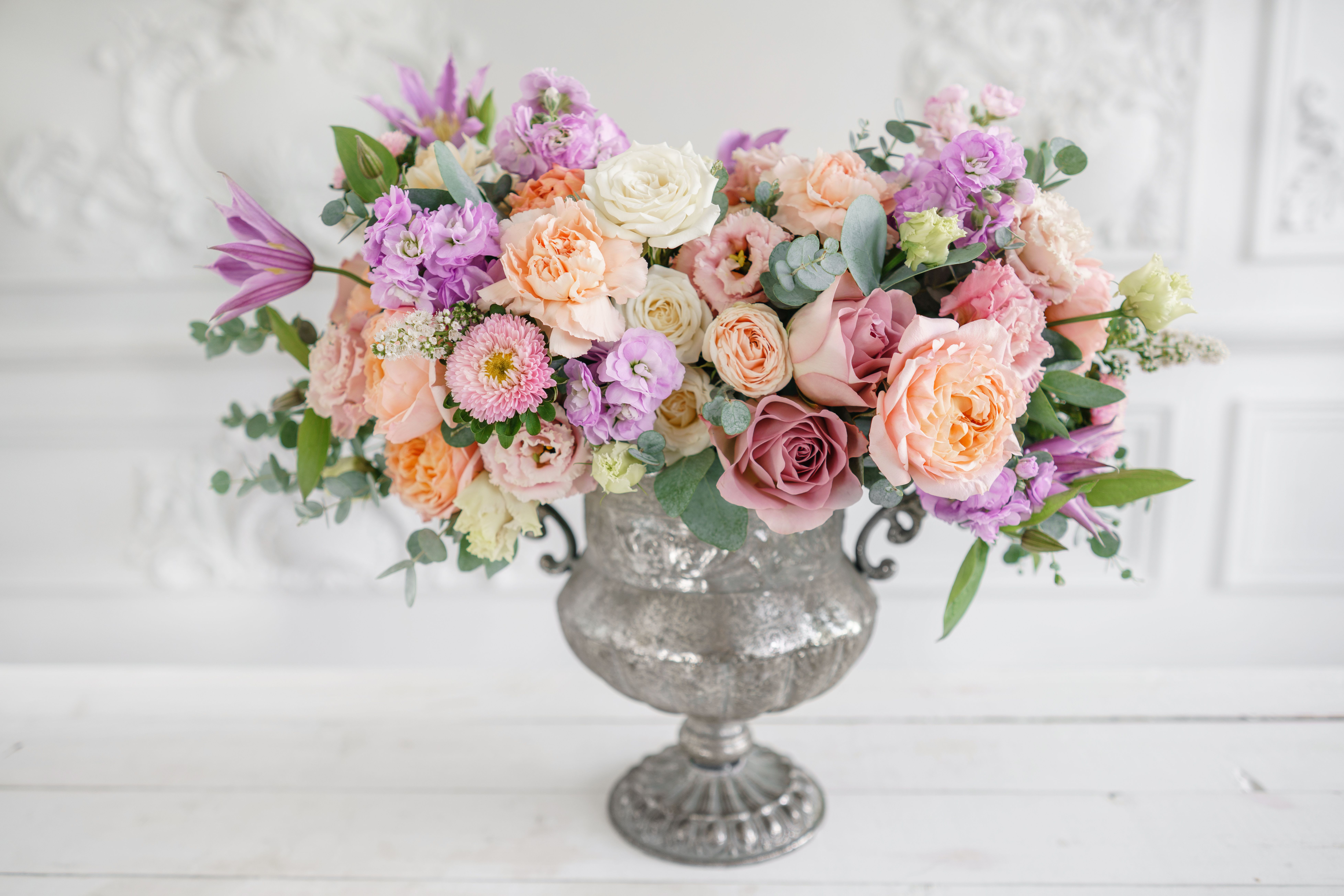 Pastel bouquet of roses and mixed blooms in a silver urn vase