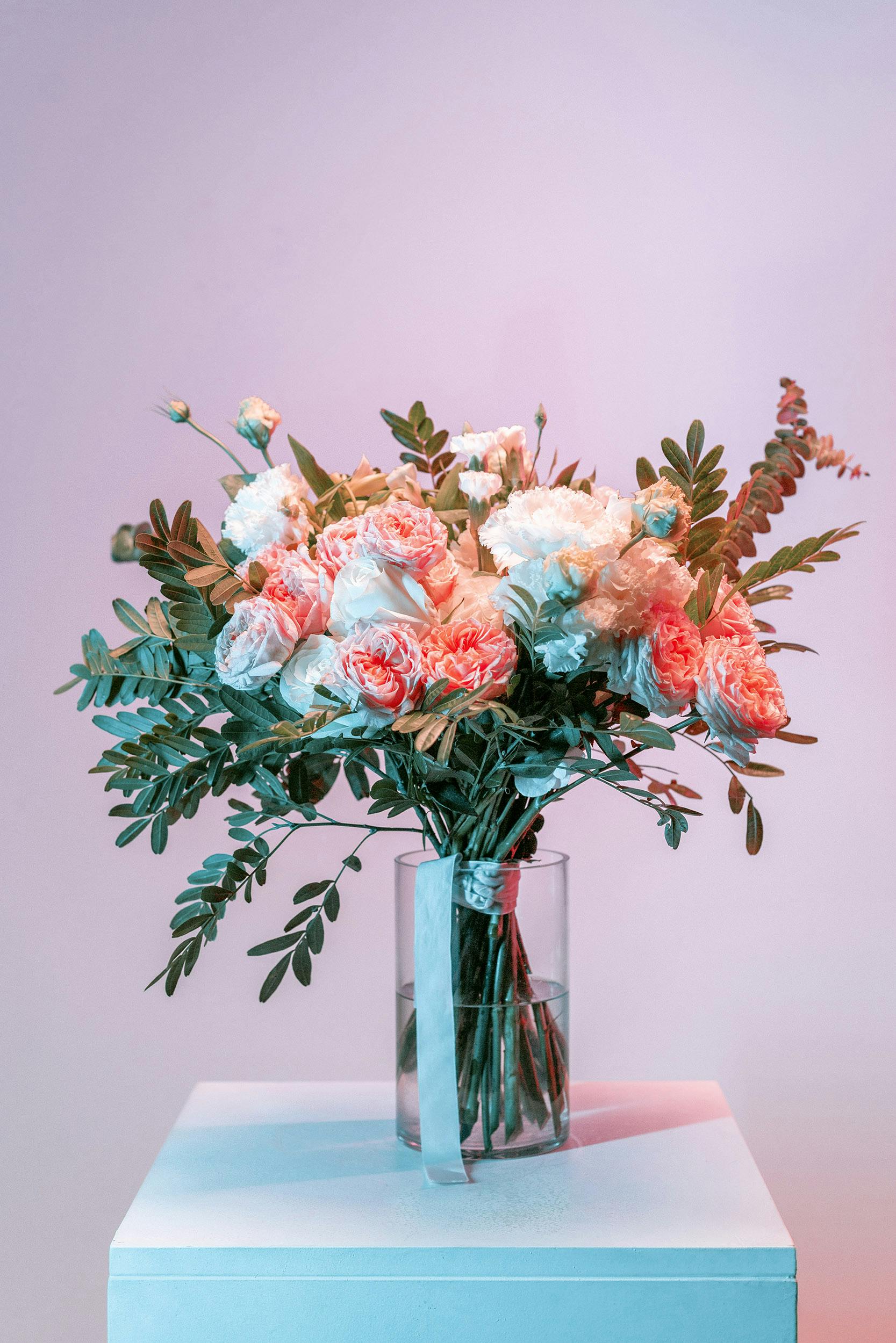 Pink and white bouquet in a clear glass vase with trailing greenery
