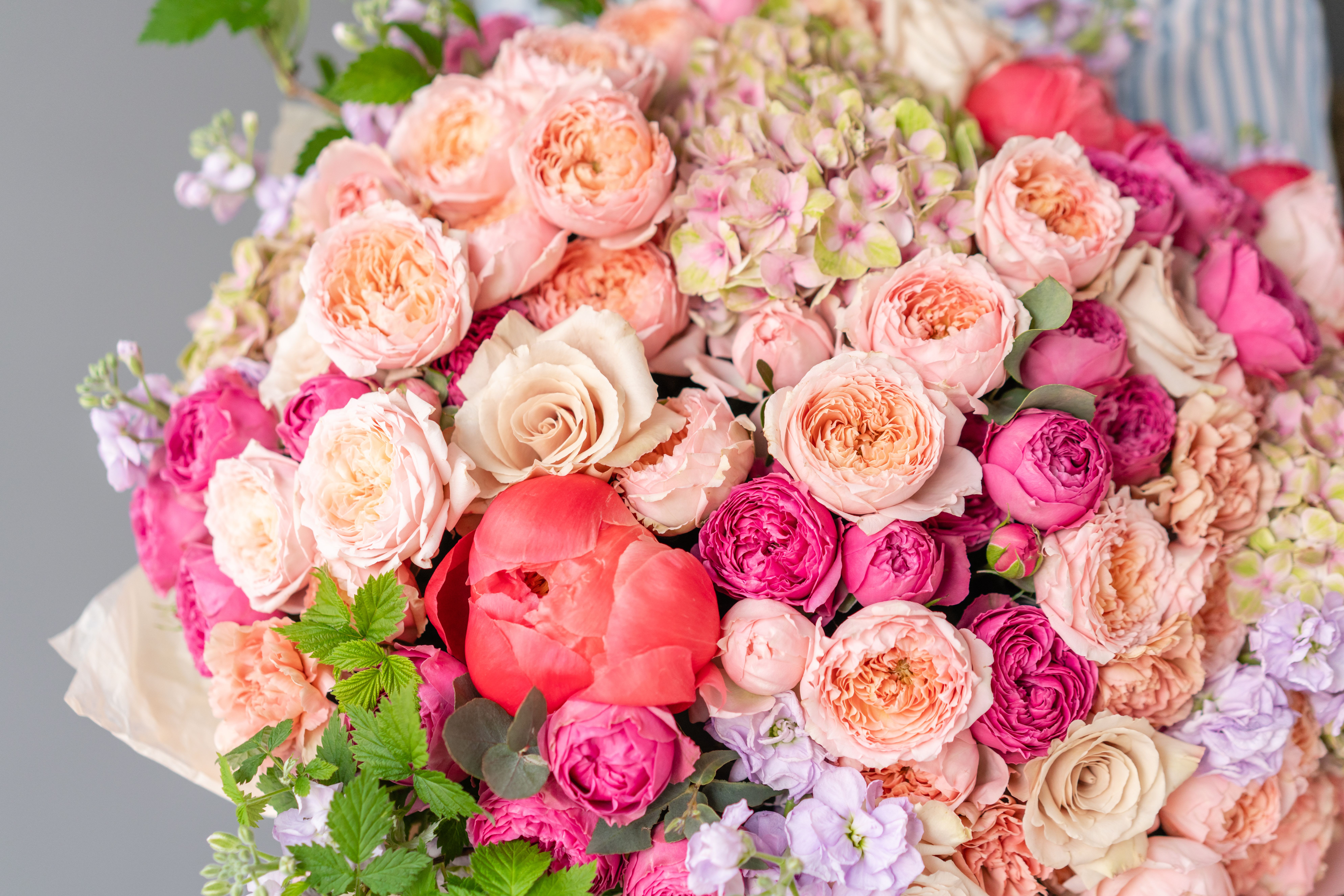 Large bouquet of pink and peach roses with a coral peony