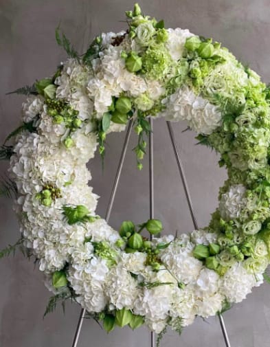 White and green floral wreath on a metal stand