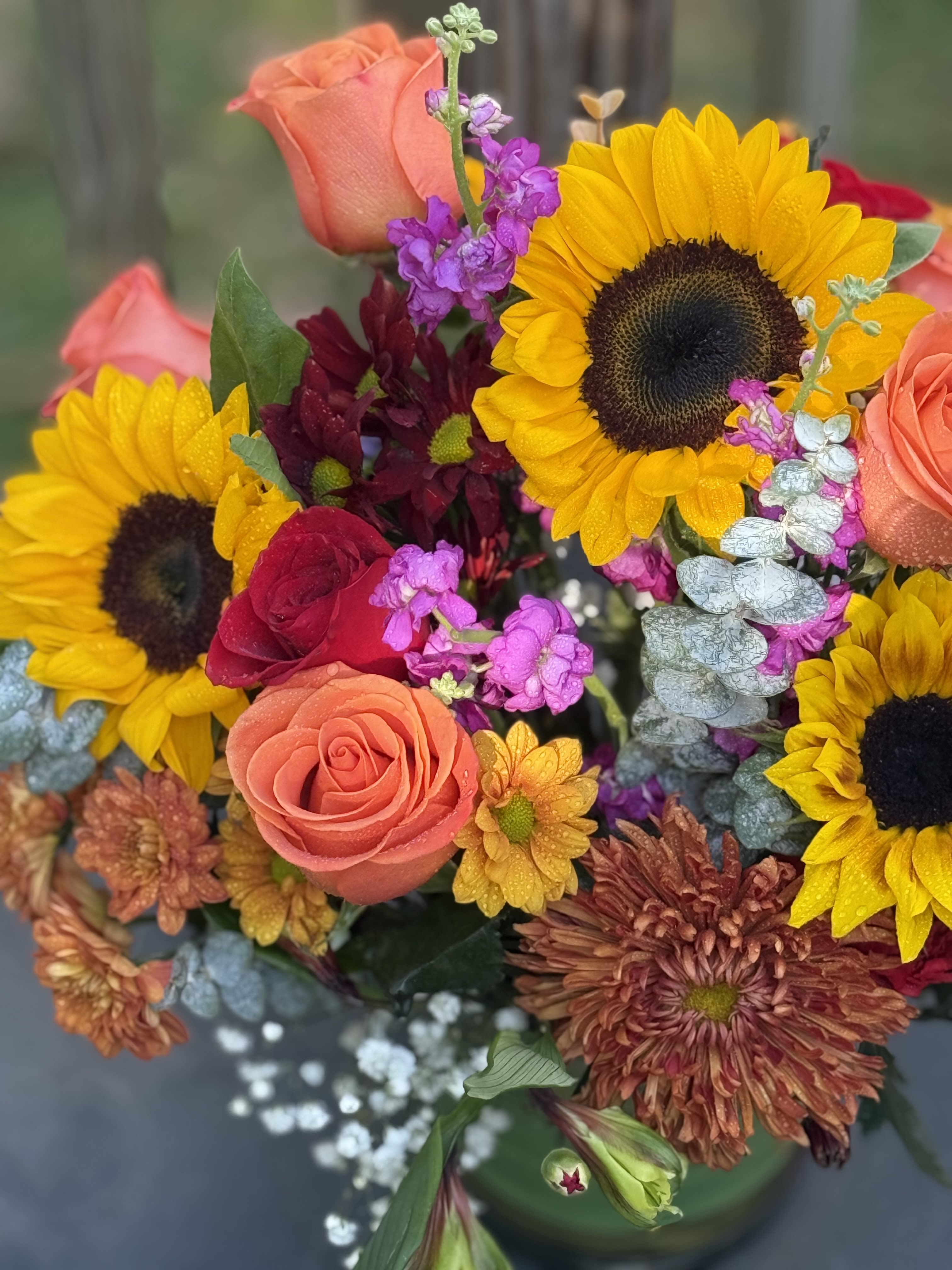 Bouquet of sunflowers, roses, and purple filler flowers