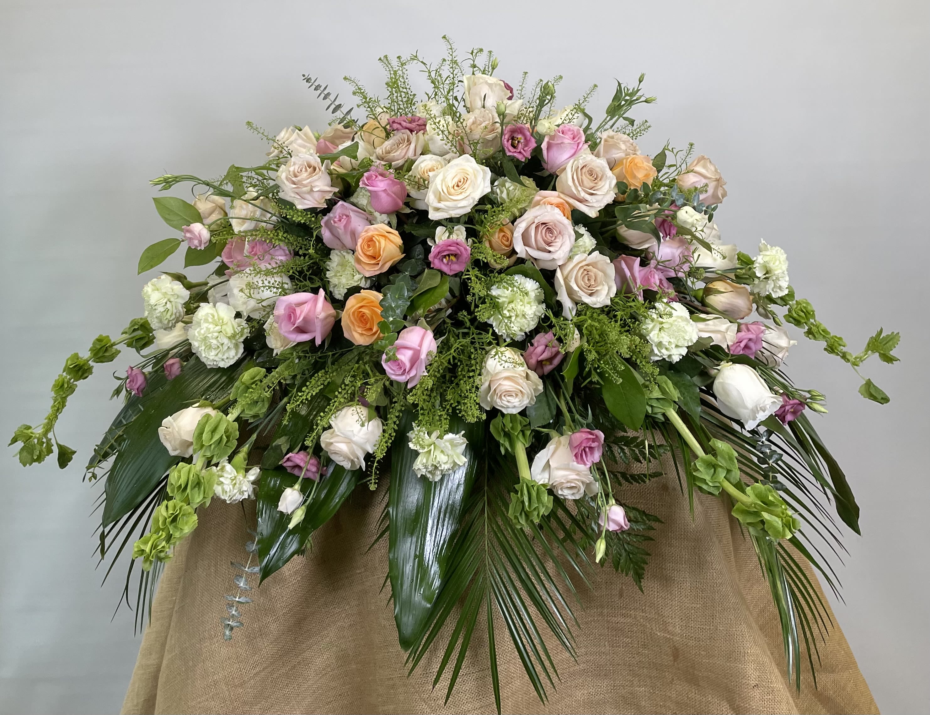 Large pastel bouquet of roses and carnations with trailing greenery