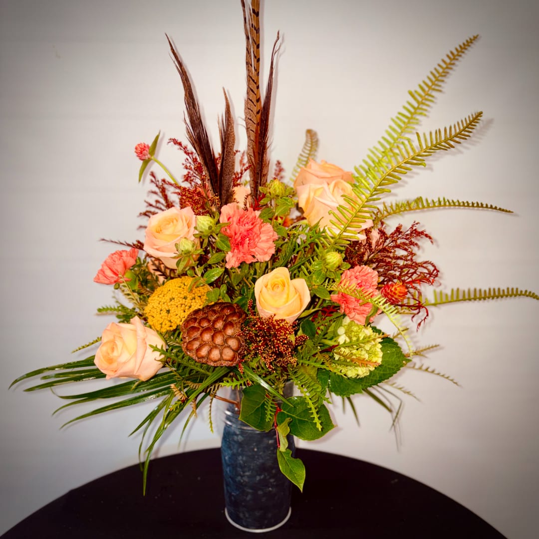 Peach roses and coral carnations in a tall blue vase