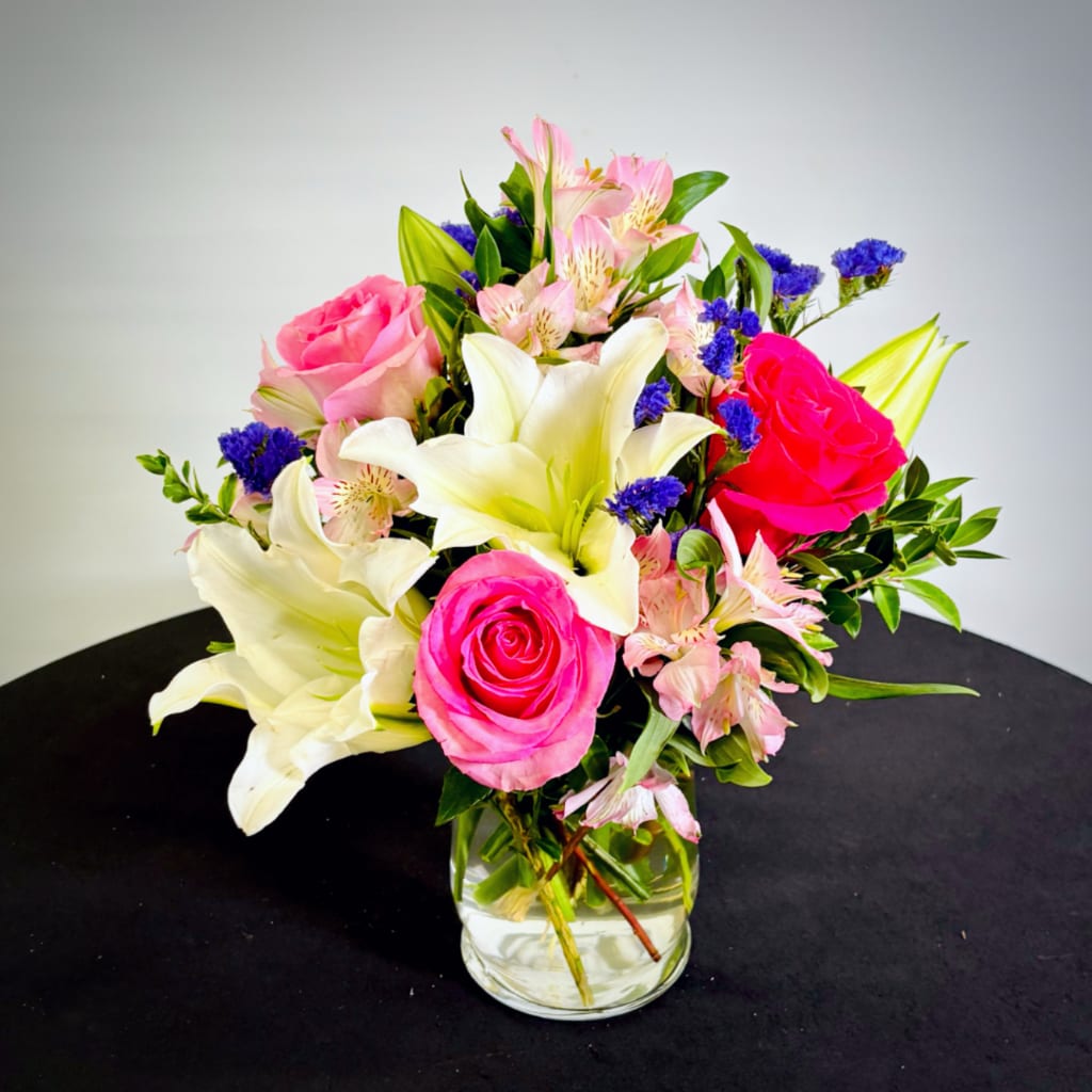 Bouquet of pink roses, white lilies, and pink alstroemeria in a glass vase