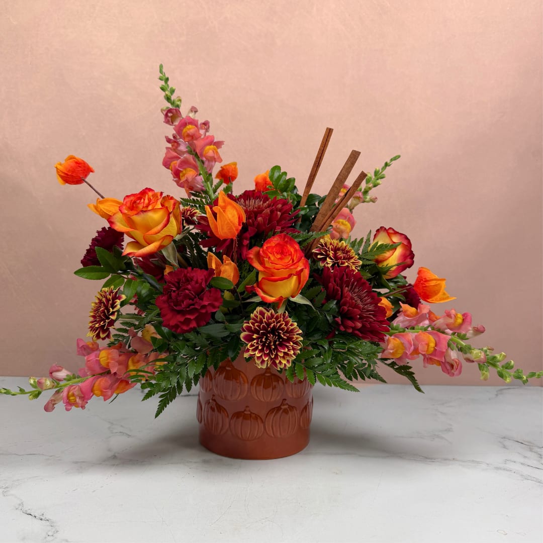 Mixed orange, pink, and burgundy flowers in a brown vase
