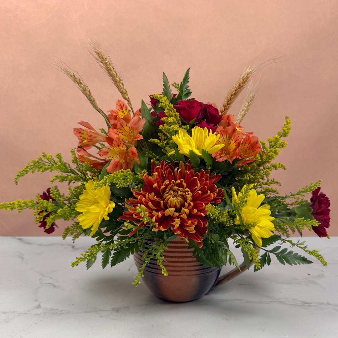 Mixed bouquet in a copper mug with red, yellow, and orange flowers