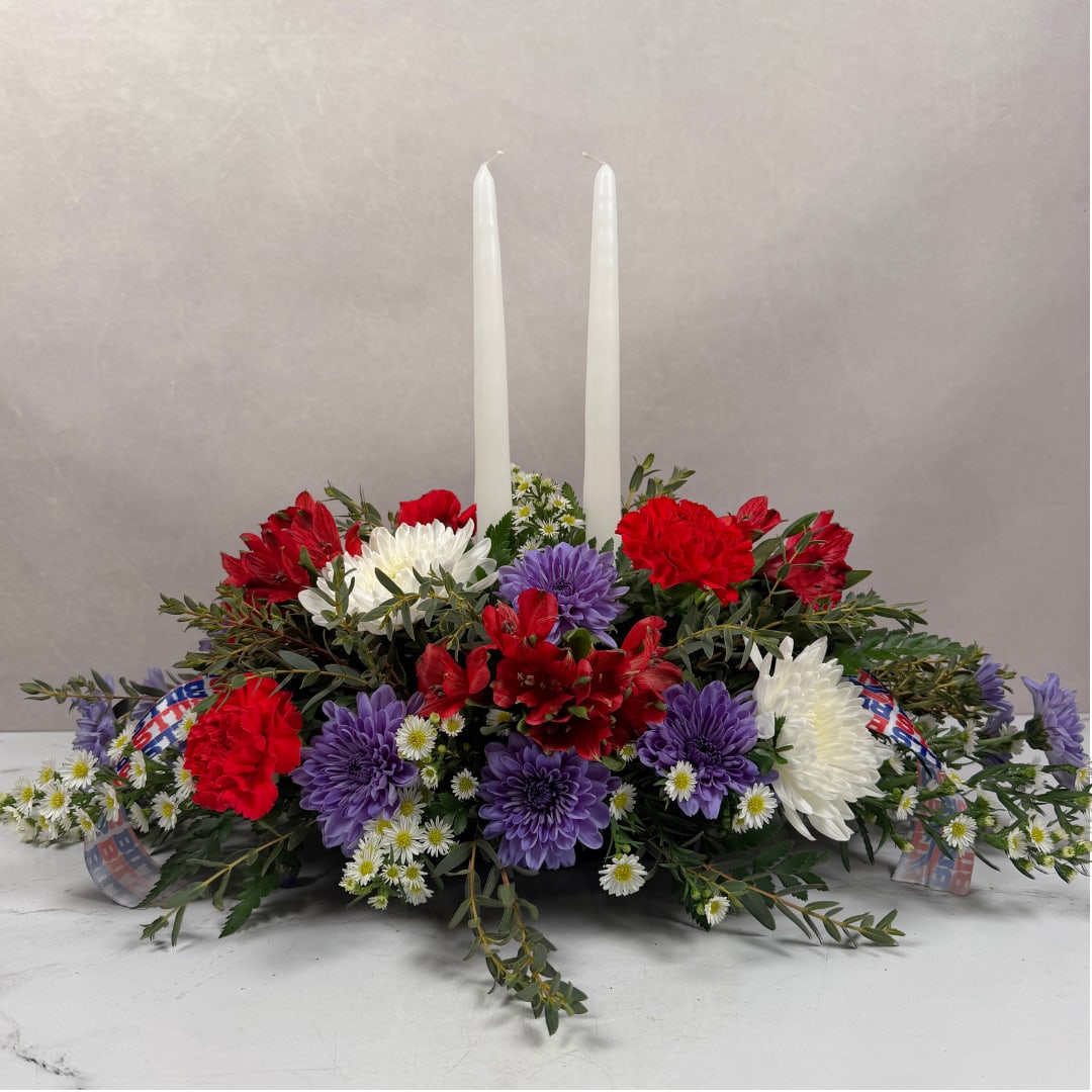 Red, white, and purple floral centerpiece with two tall white candles