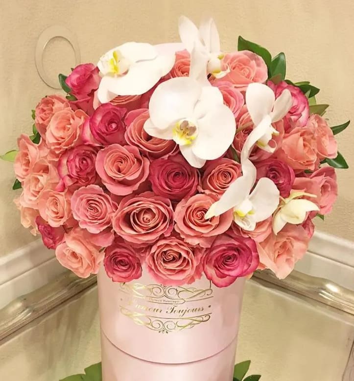 Pink and peach roses with white orchids in a pink hat box