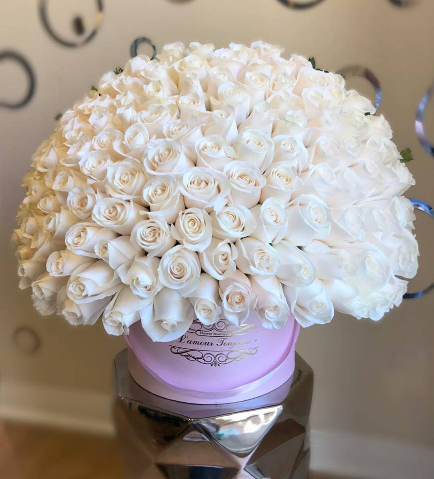 Large round bouquet of white roses in a pink hat box
