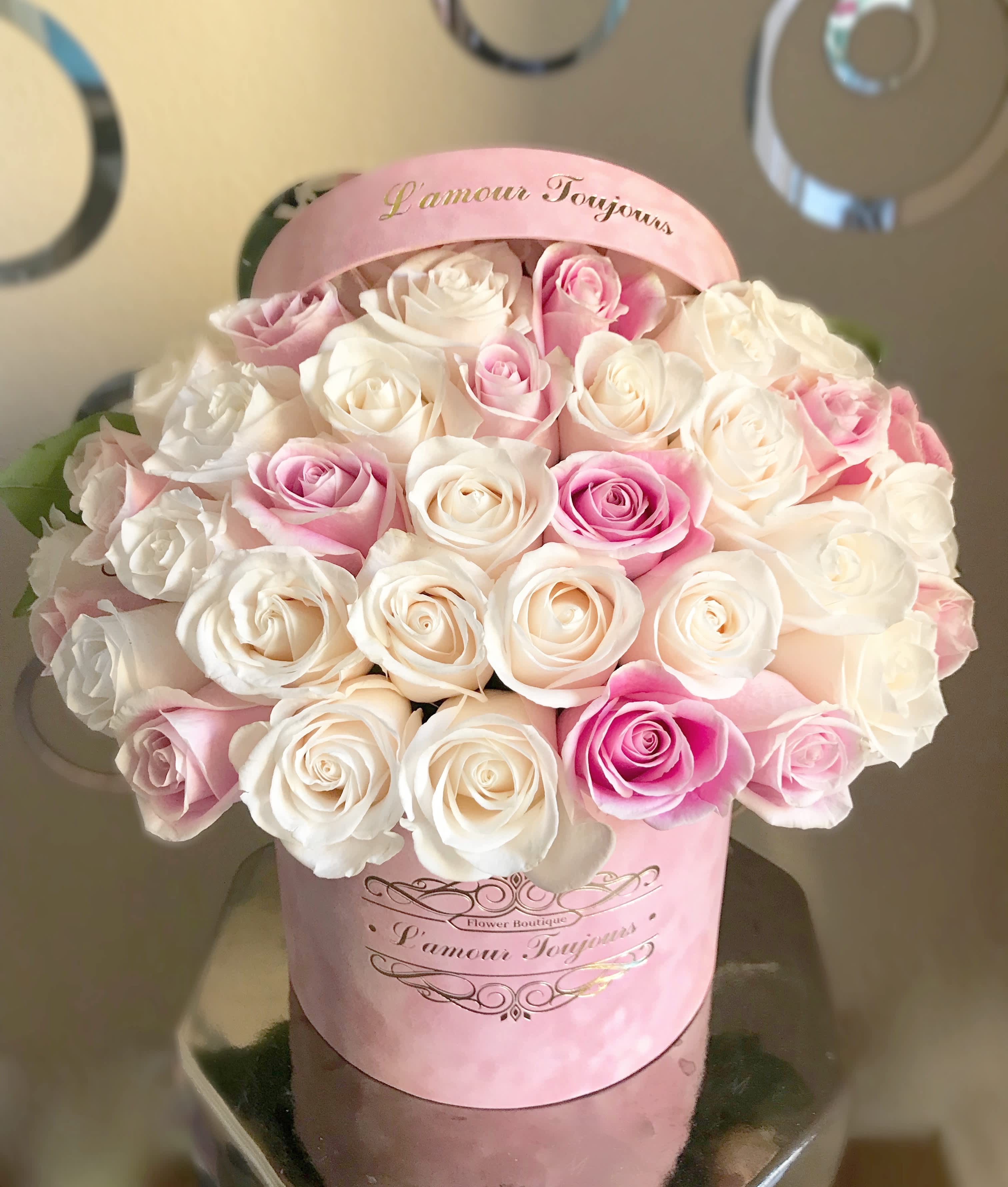 Pink and white roses arranged in a pink hatbox