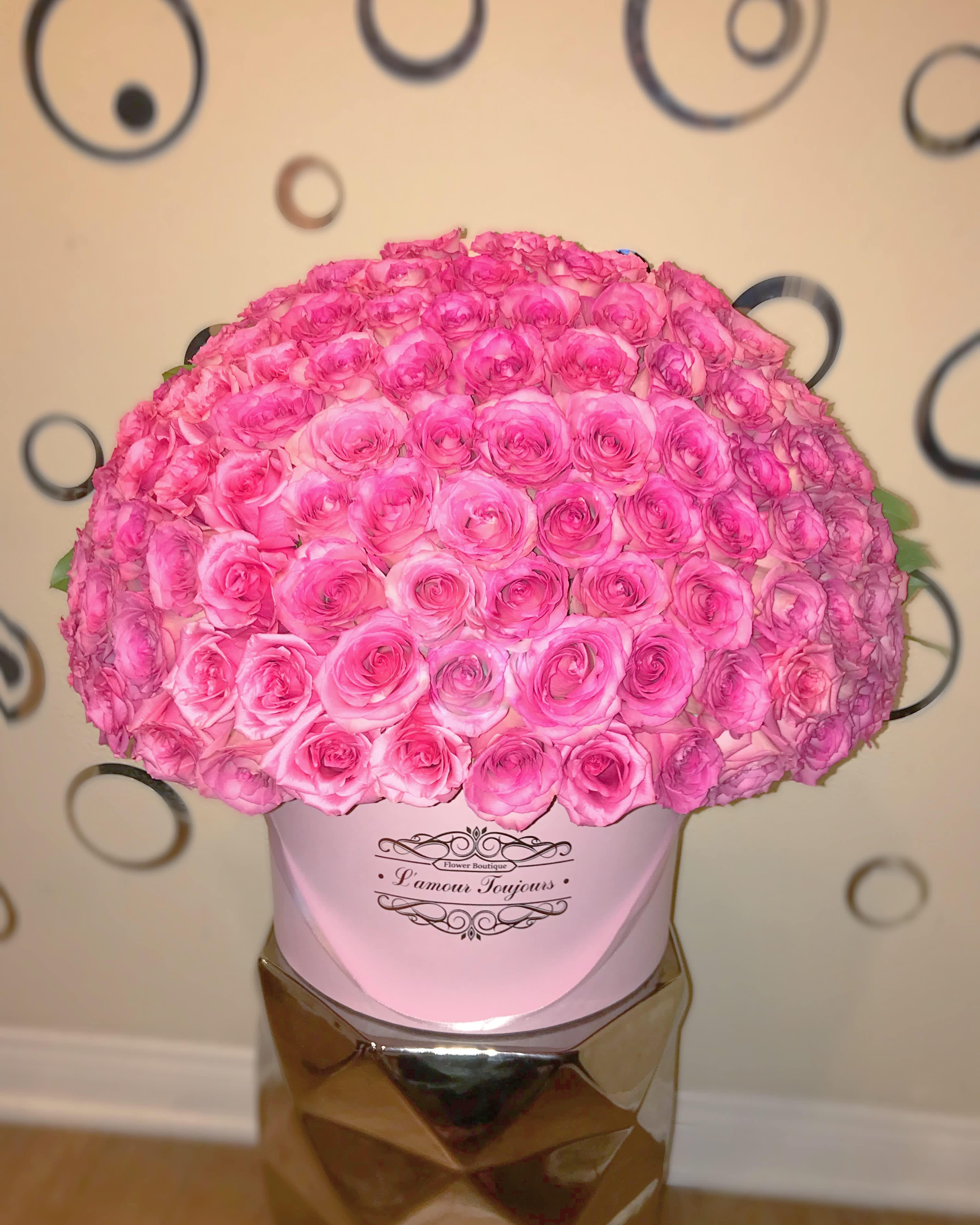 Large pink rose arrangement in a pink hat box on a mirrored stand