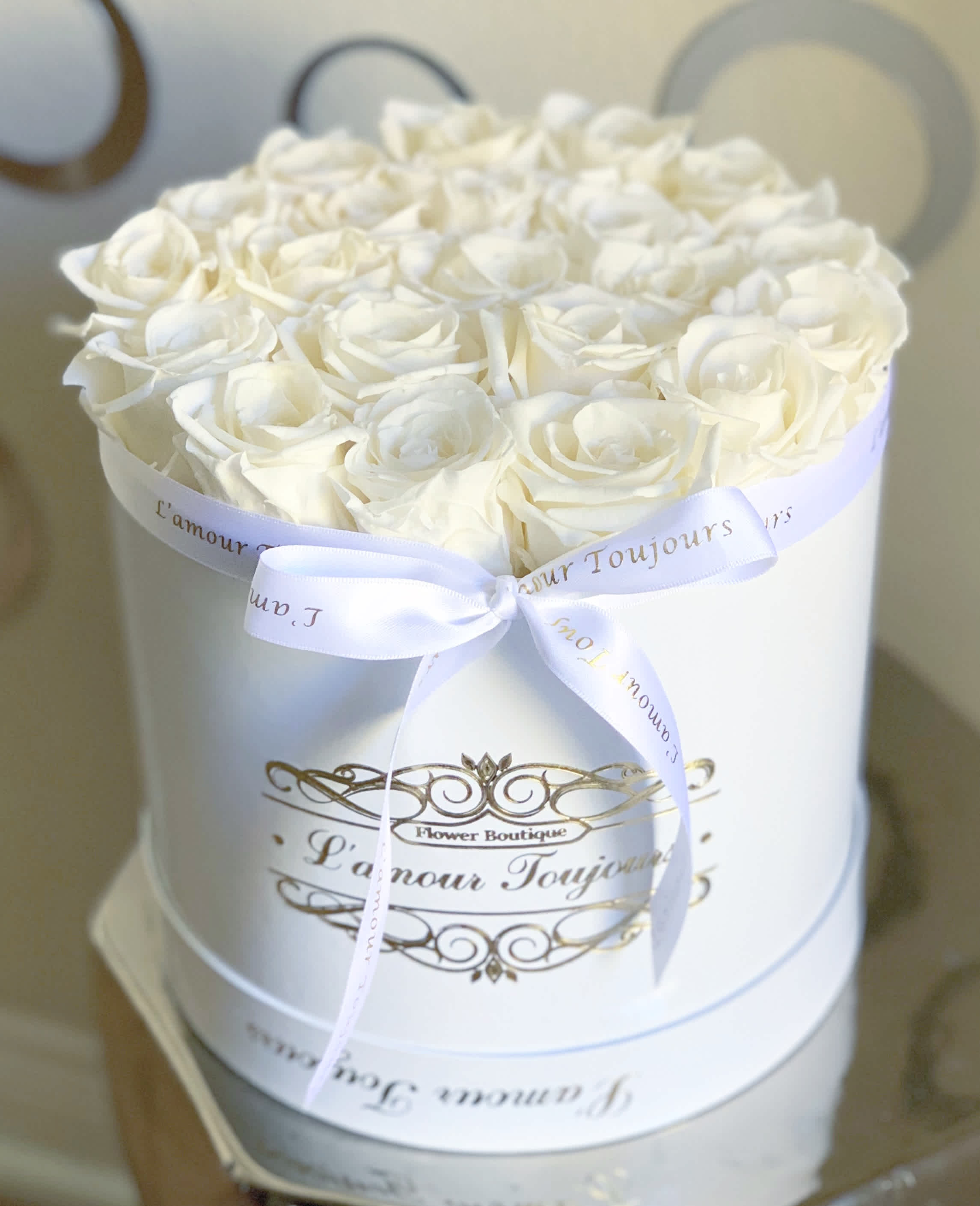 White roses arranged in a round white box with a ribbon bow