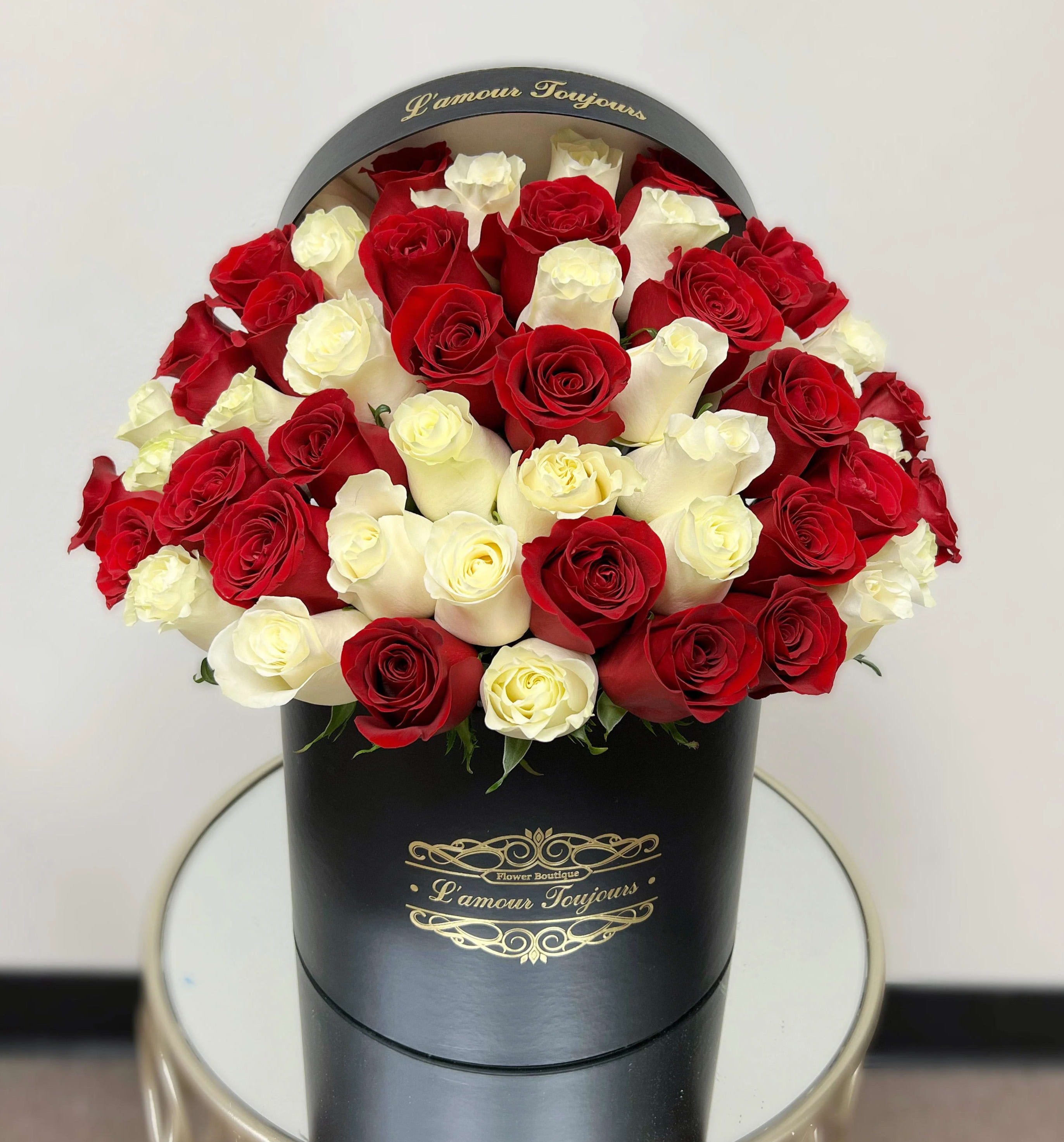 Red and white roses arranged in a black round box