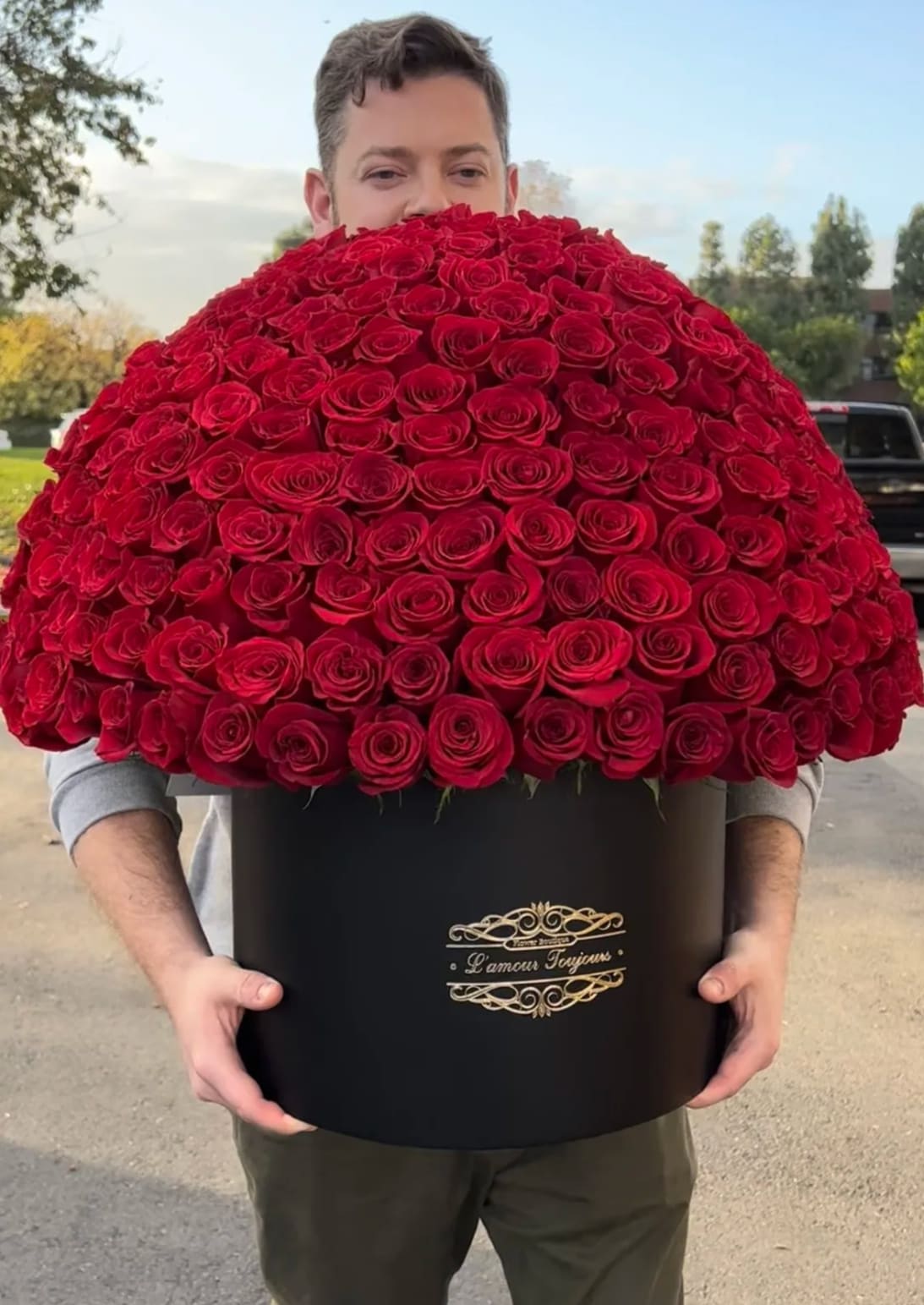 Man holding a large black box filled with red roses