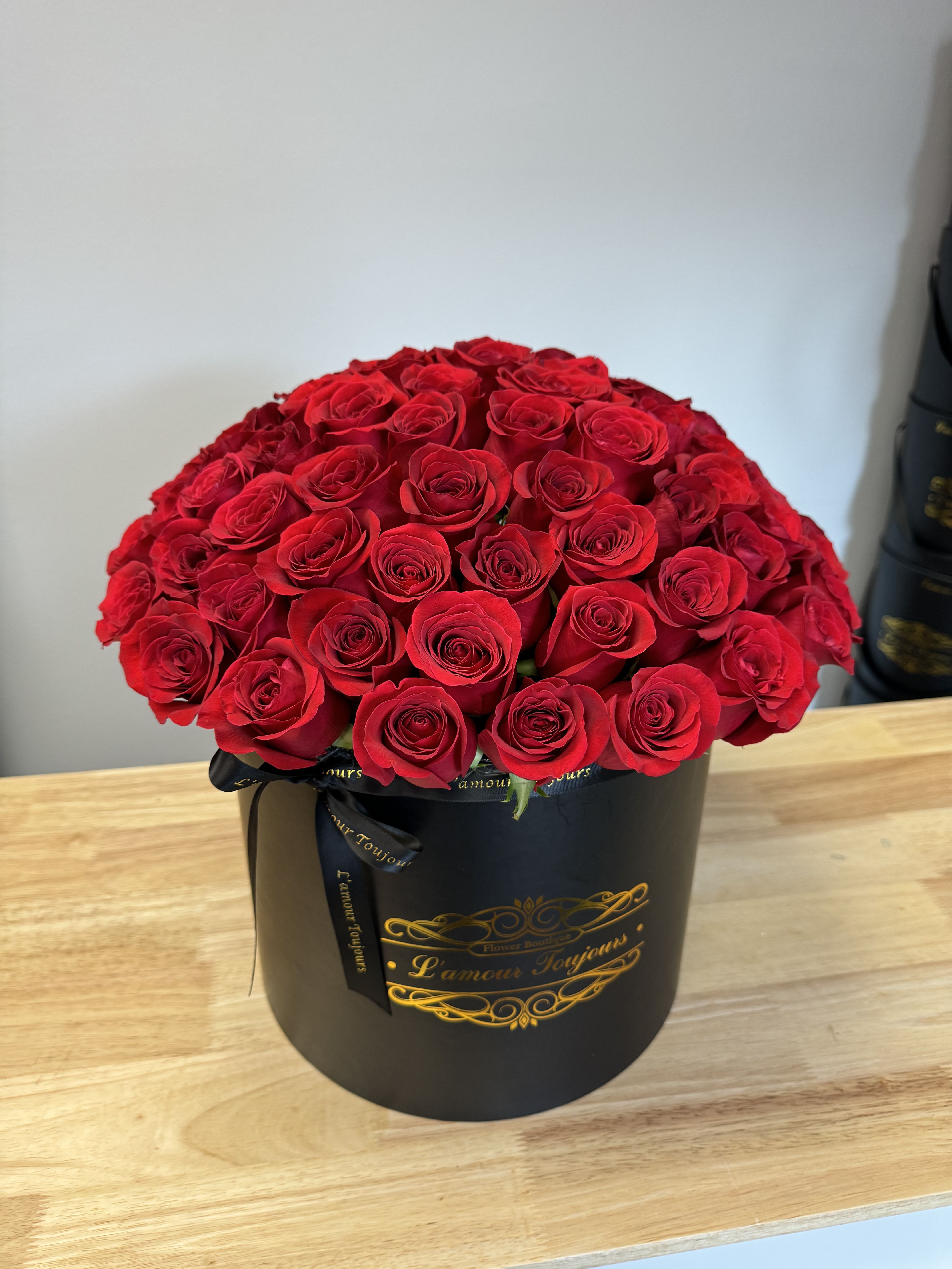 Red roses arranged in a black round box with a ribbon
