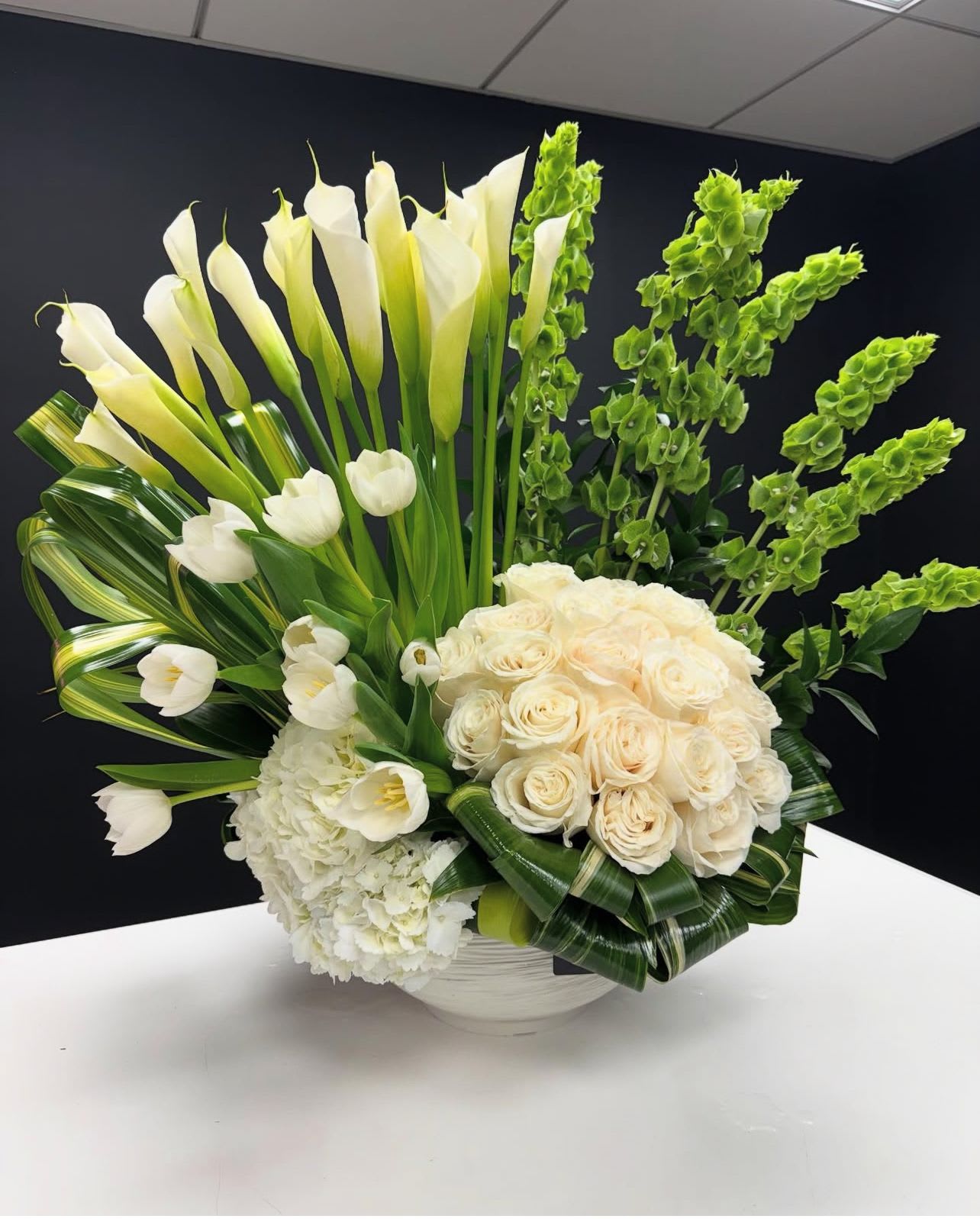 Grand Floral Statement, - Make a breathtaking impression with "Grand Floral Statement," an extra-large modern arrangement overflowing with lush roses, elegant calla lilies, vibrant tulips, and voluminous hydrangeas. This dramatic display of color and texture is a showstopper, perfect for making a grand entrance or creating a truly unforgettable centerpiece.  *vase will be a Luxe designer choice dish which will not disappoint!   