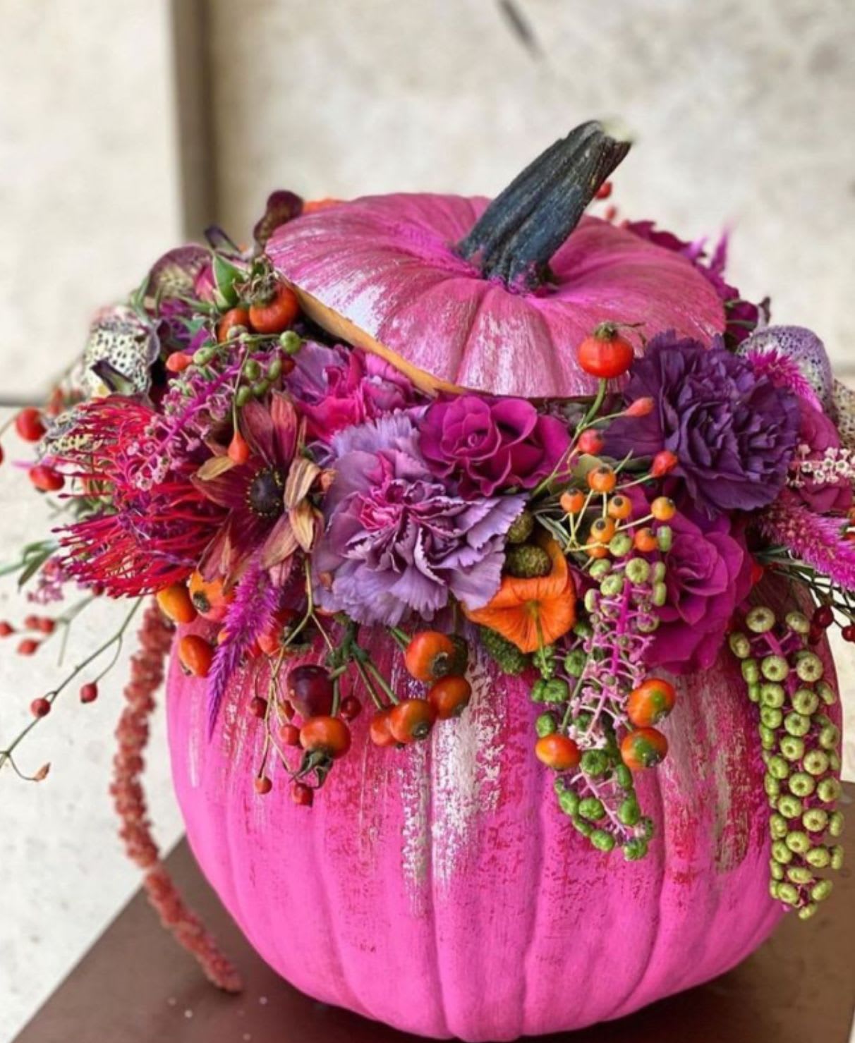 Enchanted Dream Pumpkin - Add a touch of whimsy and elegance to your fall décor with our Enchanted Dream Pumpkin, exclusively at Braly Blooms. This hand-painted pink fresh pumpkin is artfully designed with a lush blend of deep pink and purple florals from our in-store collection. Romantic, modern, and full of charm, this arrangement brings a feminine twist to traditional autumn designs — perfect for gifting, styling, or making a bold seasonal statement.