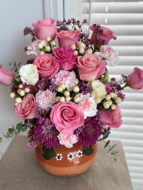 Cozy Pot - Floral arrangement with a mixture of roses, carnations, mums, and more in a clay vase.   If a particular flower, is unavailable, an item of similar quality and value will be substituted.