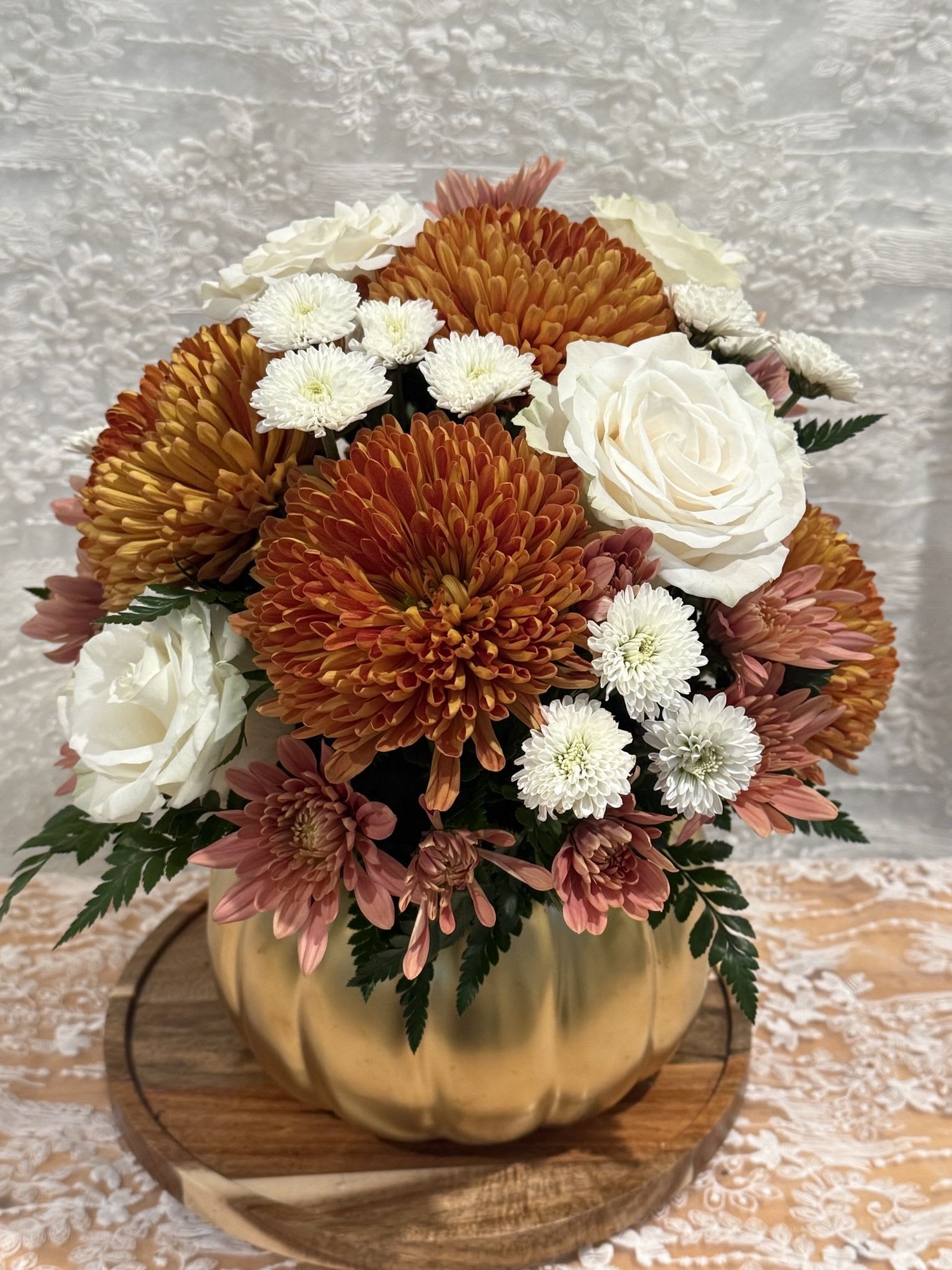 Golden Fall - Gold pumpkin filled with white roses and golden tone mums.   If a particular flower, is unavailable, an item of similar quality and value will be substituted.
