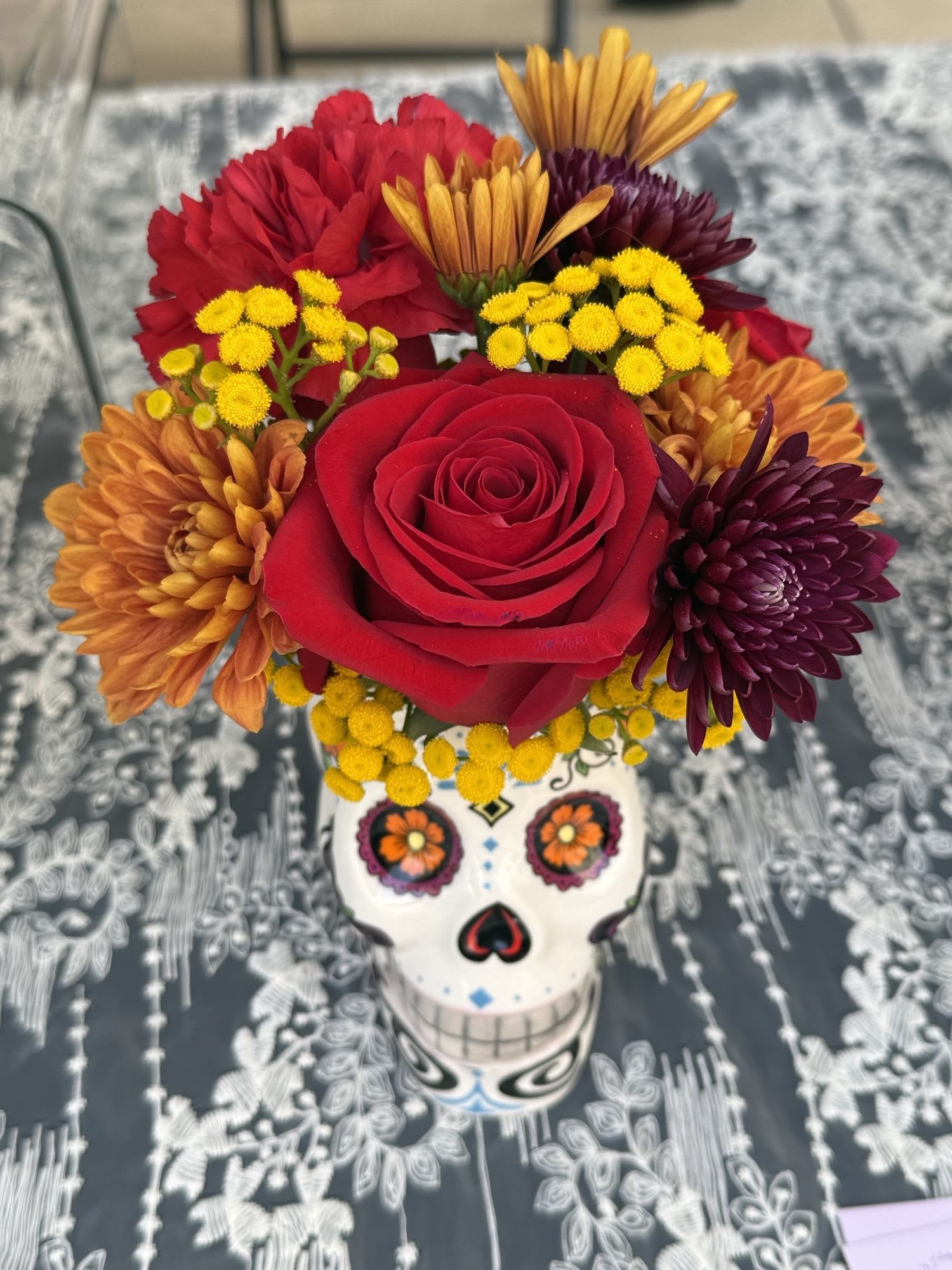 Catrina - Designers' choice. Day of the dead skull with fall flowers  If a particular flower, is unavailable, an item of similar quality and value will be substituted.