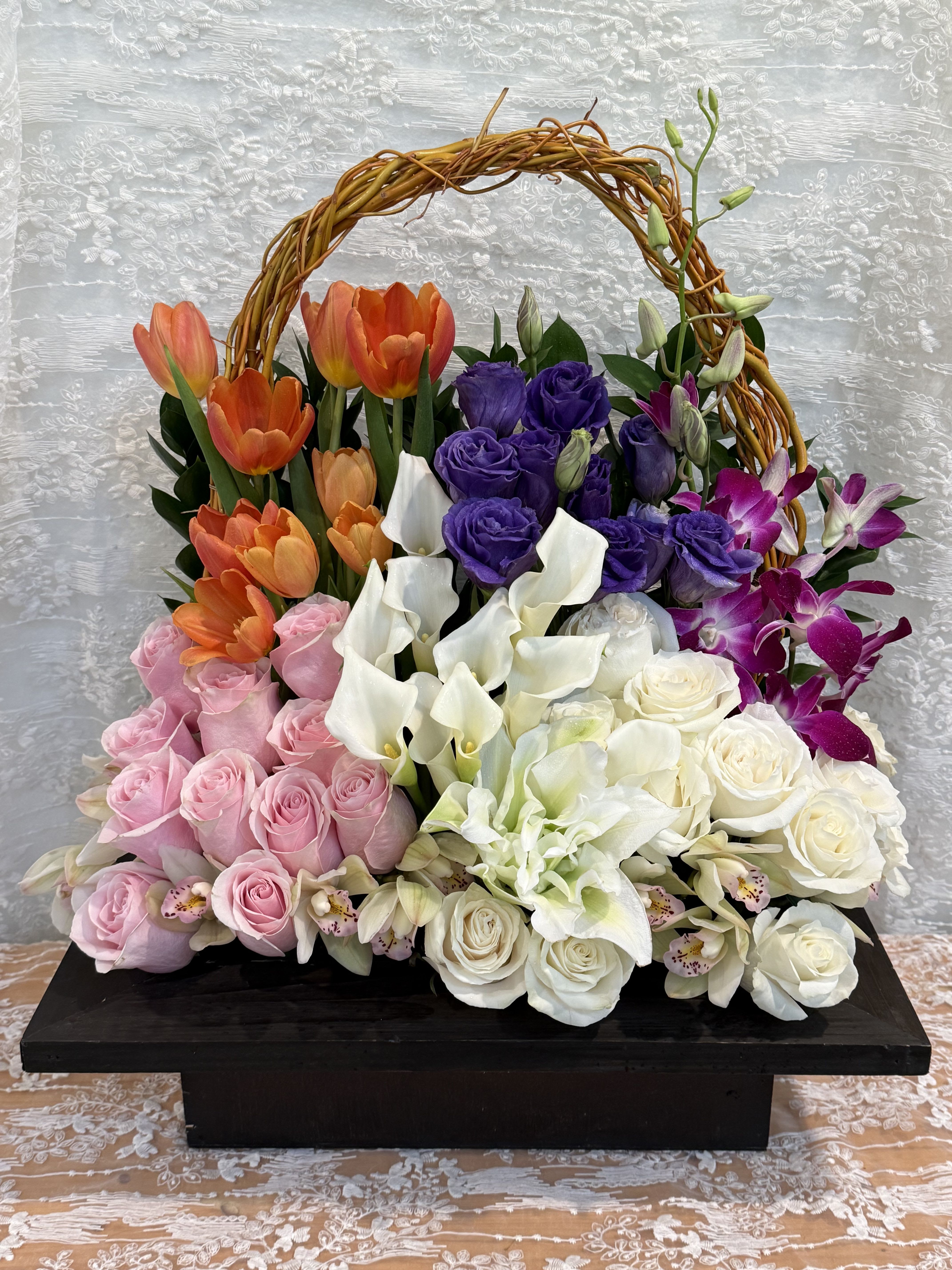 Celebration - Grand floral arrangement filled with roses, tulips, lilies, lisianthus tied together with a handle made out of curly willow.    If a particular flower, is unavailable, an item of similar quality and value will be substituted.  