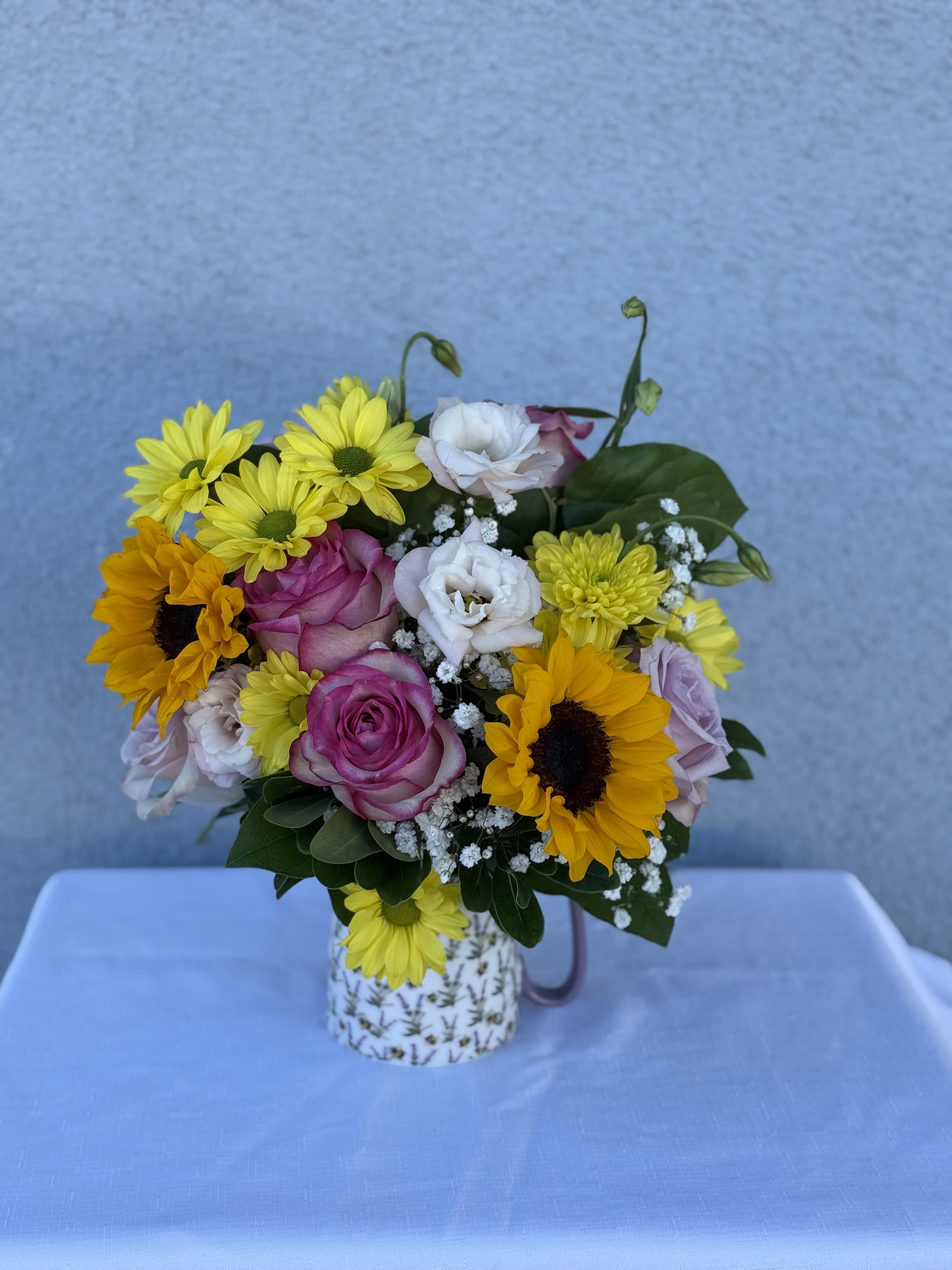 Buzzing Bloom - Bee coffee mug filled with daisies, sunflowers, roses and lisianthus.  Arrangement comes in a Bee coffee mug 