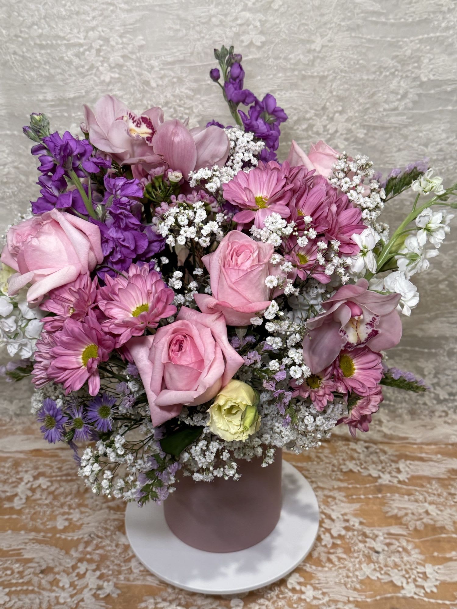 XOXO Pink - Lisianthus, Orchids, Roses, Stock flowers, spray Mums and Asters in a light pink vase.