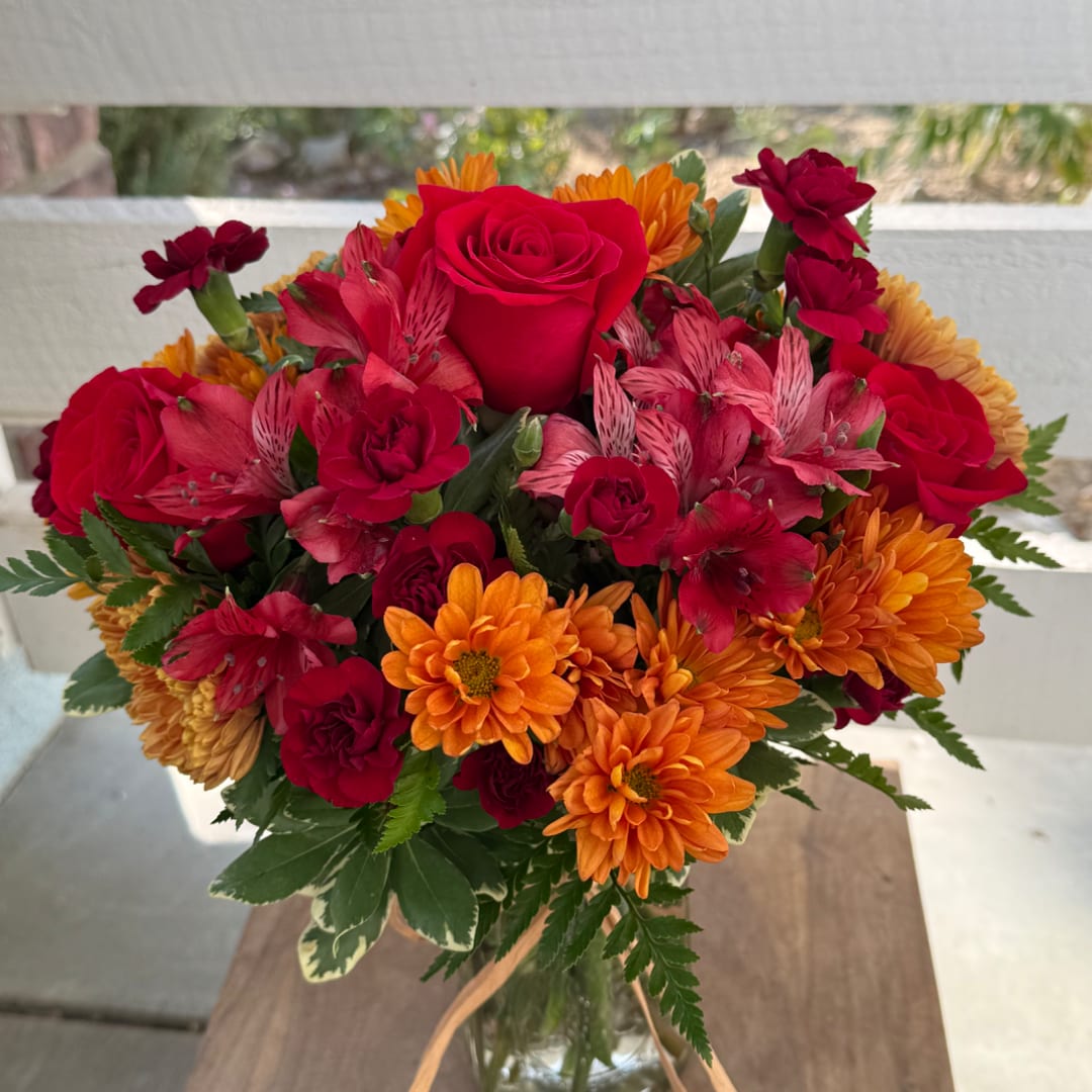 Red roses and orange chrysanthemums in a glass vase